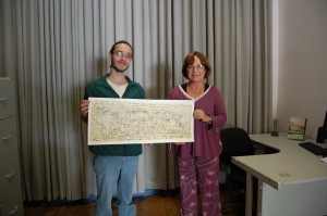 O Gerente Operacional do Núcleo de História Oral, Eder Melo e a ex-entrevistada do Vale Registrar, Anna Amélia Lopes de Oliveira, seguram o exemplar do Roteiro Etílico de Ouro Preto, na Sala de Histórias, da Estação Ferroviária de Ouro Preto. Foto: Rafael Santos