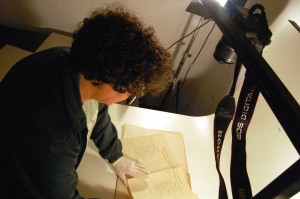 Josanne Simões, assessora técnica do Núcleo de História Oral do Vale Registrar, seleciona documento da Companhia Industrial Ouropretana para ser fotografado, no Vagão de Oficina de Vídeo da Estação Ferroviária de Mariana. Foto: Marianne Fonseca