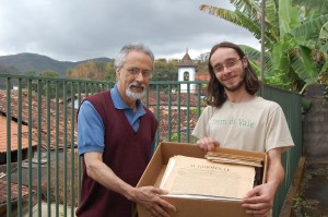 O pesquisador Eder Melo e o entrevistado do Vale Registrar, Rafael Arcanjo Santos, proprietário do acervo de antigos jornais de Mariana, seguram os exemplares emprestados em sua residência, na Rua Direita, em Mariana. Foto: Wesley Souza 