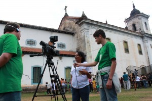 A equipe do Vale Registrar – Leonardo Penna (Gerente Operacional do Núcleo de Audiovisual) e André Sousa (estagiário do Apoio Técnico-Administrativo) – gravam depoimento de Margarida Angélica Gonçalves Moreira, ao lado da Igreja Nossa Senhora do Rosário, momentos antes da 5ª exibição da Mostra de Videocabines, no distrito de Padre Viegas, em Mariana. Foto: Wesley Maurício