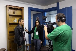 A equipe do Núcleo de Audiovisual do Vale Registrar – Leonardo Penna (Gerente Operacional) e Isadora Bruzzi (estagiária) – gravam depoimento de Aldo Macário de Paula, morador do bairro Padre Faria, momentos antes da 4ª exibição da Mostra de Videocabines, no Bairro Padre Faria, em Ouro Preto. Foto: Cristiane Evangelista