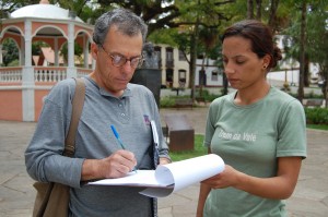 O depoente Leonardo Moyle Baêta, preenche o Termo de Autorização para uso de imagem, orientado por Cristiane Evangelista, da equipe do Apoio Técnico-Administrativo do Vale Registrar, na Praça Gomes Freire, em Mariana. Foto: Marianne Fonseca 