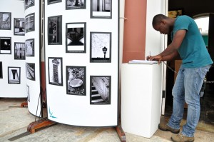 O aluno da 7ª Oficina de Fotografia Digital, Marllon dos Santos Bento, assina caderno de registro da Exposição Fotográfica, na plataforma da Estação Ferroviária de Mariana. Foto: Isadora Bruzzi
